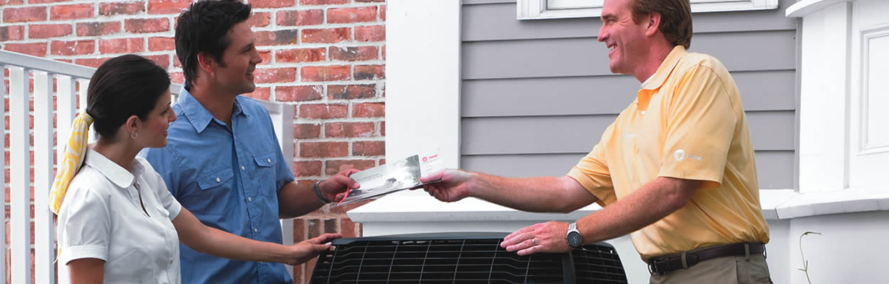 Hvac Tech Handing Brochure To Homeowners While Standing Next To Trane Ac Unit 1